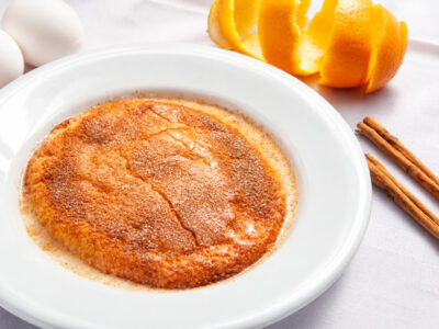 Plato hondo blanco con bizcocha manchega empapada y espolvoreada con azúcar y canela.