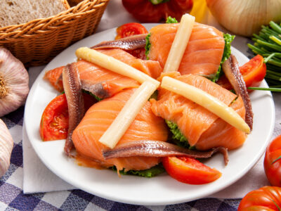 Ensalada de cogollos, salmón ahumado, anchoas y espárragos blancos sobre mantel de cuadros.