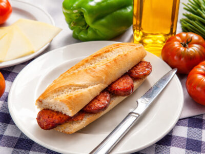 Montado de chorizo de pastor en pan de barra sobre un plato blanco.